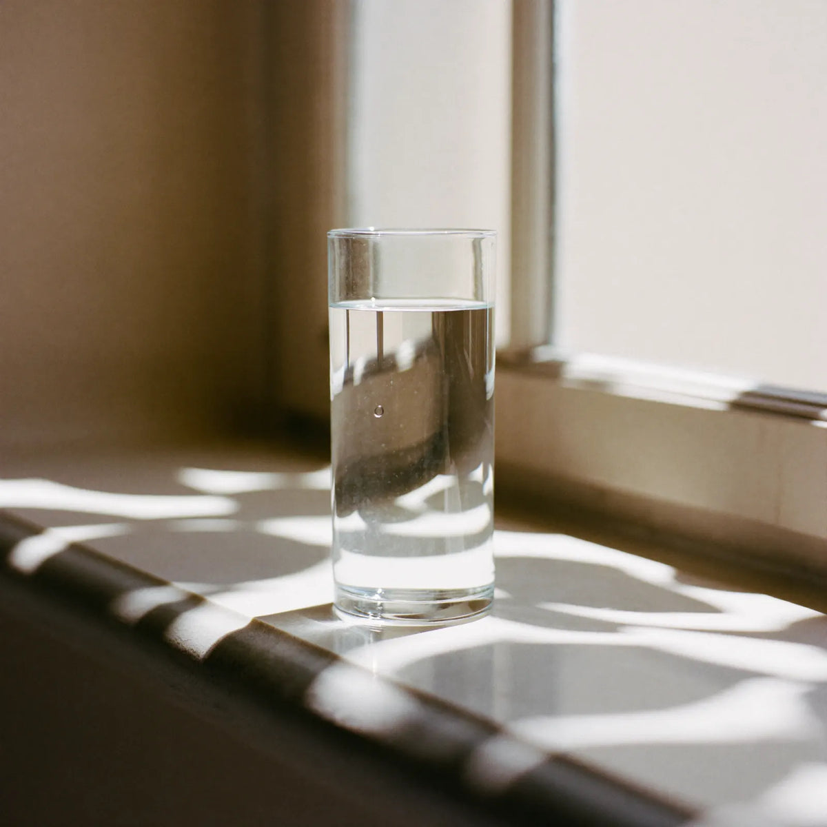 A glass of water standing beside a chrome single-lever tap