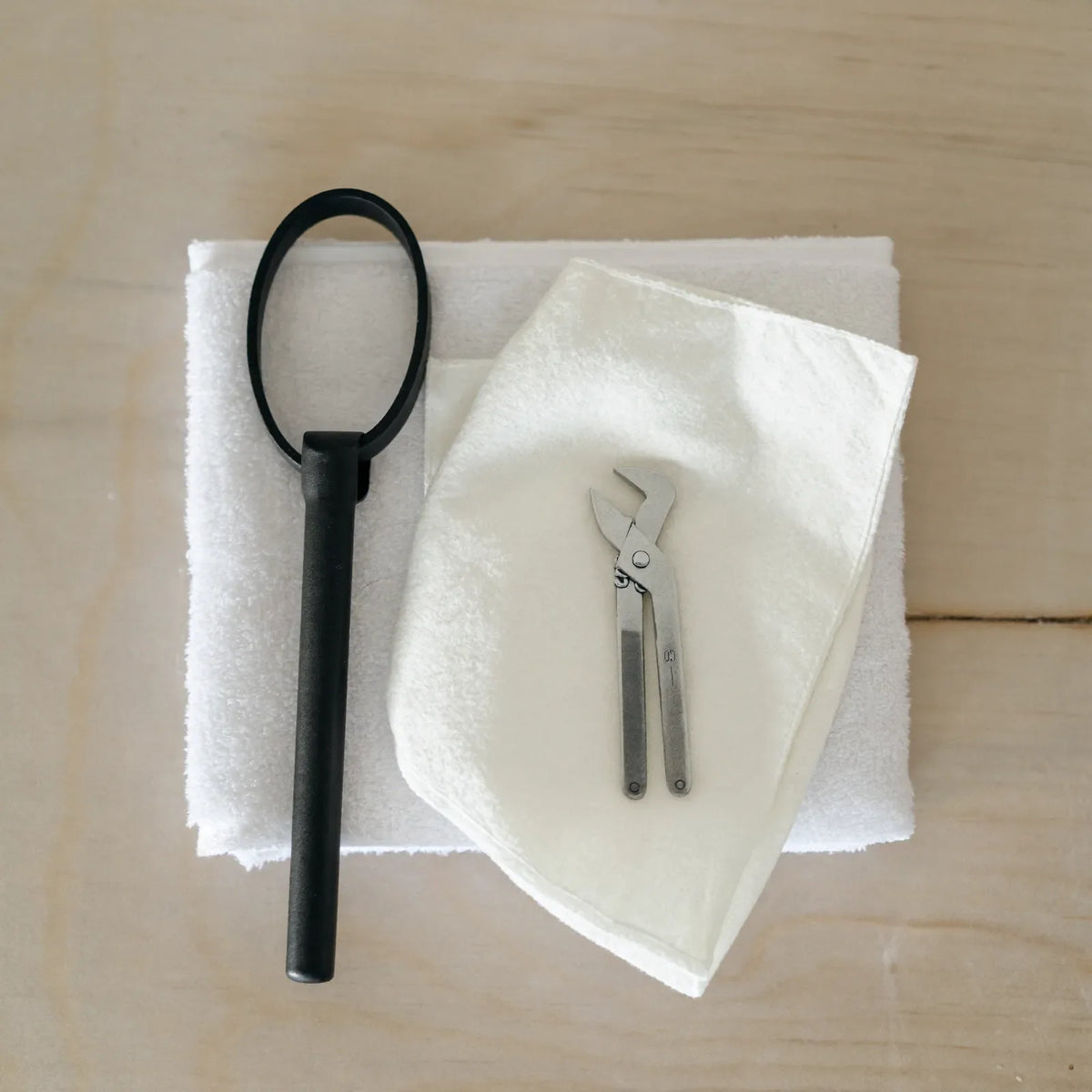 A calm white bathroom with a chrome handheld shower head and its hose resting on the edge of a bath