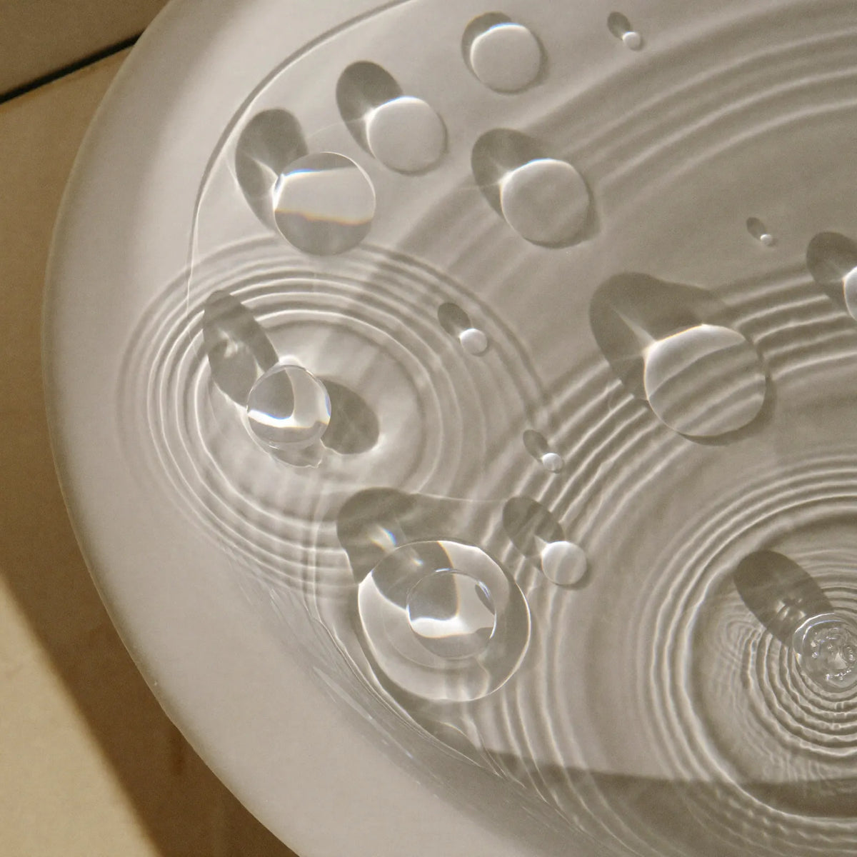 Water running from a chrome wall-mounted tap into a white basin